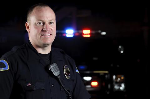 A police officer standing in front of his patrol vehicle.